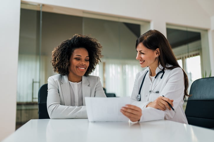 Good-news-Smiling-female-patient-and-doctor-looking-at-paper-document.-1253607505_6048x4024-1