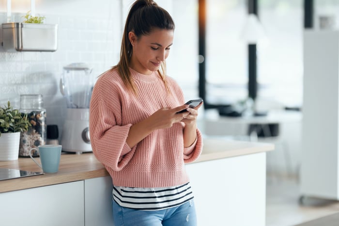 Concentrated-young-woman-sending-an-audio-with-her-mobile-phone-in-the-kitchen-at-home.-1278651929_6720x4480