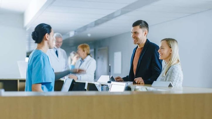 In-the-Hospital-at-the-Reception-Desk-Nurse-on-Duty-Answers-Young-Couple-Patients-and-Showing-Them-a-Way_-995338724_5120x2880-1-Jul-11-2024-08-29-28-4569-AM