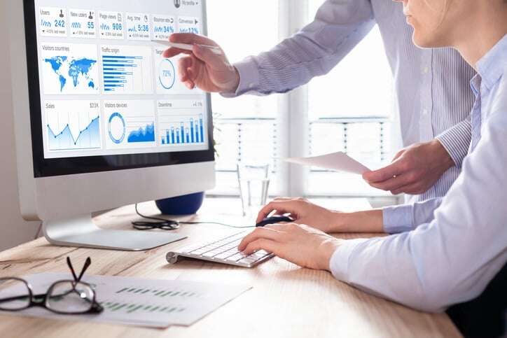Team-of-business-people-discussing-digital-marketing-metrics-report-and-return-on-investment-strategy-for-advertisement-campaign,-data-analytics-dashboard-on-computer-screen-in-office-963146264_727x484