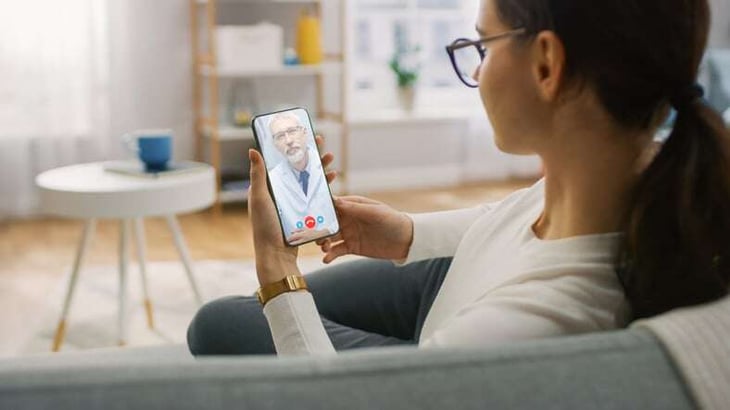 Young-Girl-Sick-at-Home-Using-Smartphone-to-Talk-to-Her-Doctor-via-Video-Conference-Medical-App.-Woman-Checks-Possible-Symptoms-with-Professional-Physician,-Using-Online-Video-Chat-Application-1265164210_792x445