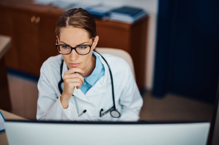 female-european-adult-doctor-consultation-room-reading-on-her-computer-print