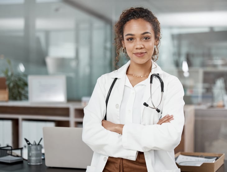female-latin-american-adult-doctor-consultation-room-portrait-standing-front-of-her-desk-web