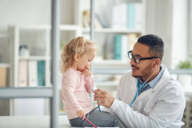 male-african-adult-doctor-consultation-room-examining-little-girl-print