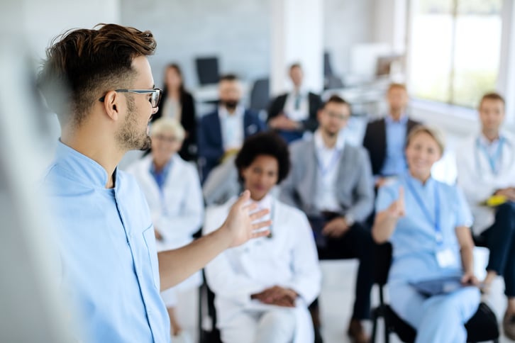 male-european-adult-doctor-clinic-talking-to-group-of-his-colleagues-during-presentation-print